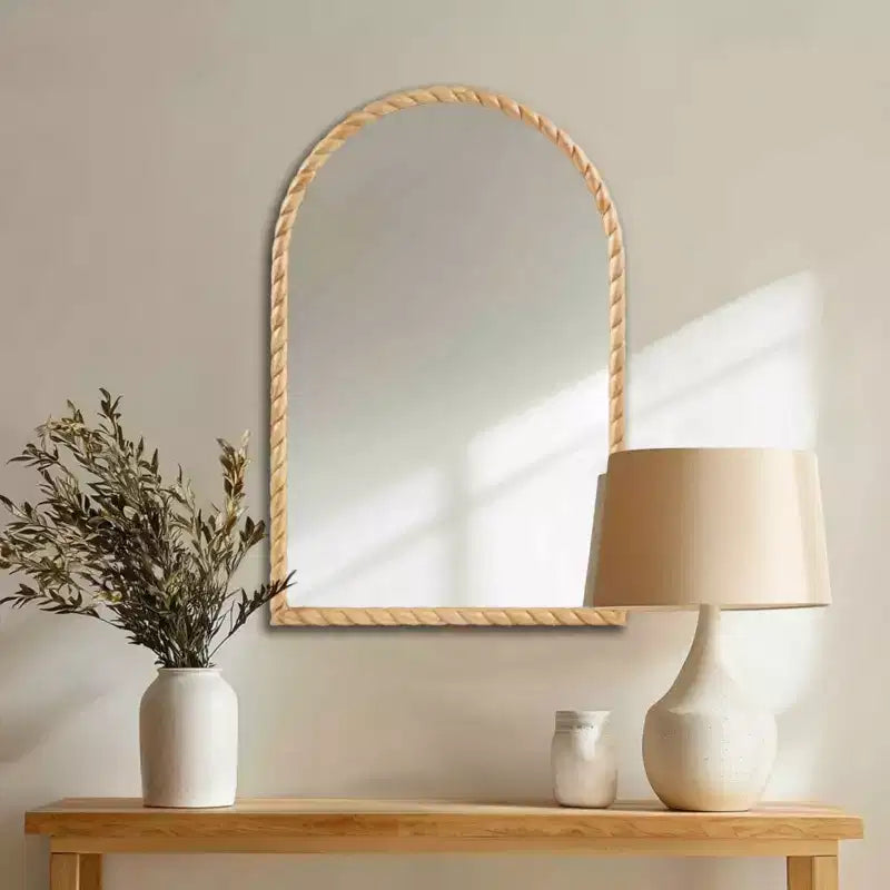 Un miroir décoratif mural arqué avec un élégant cadre en bois d'hévéa tressé.